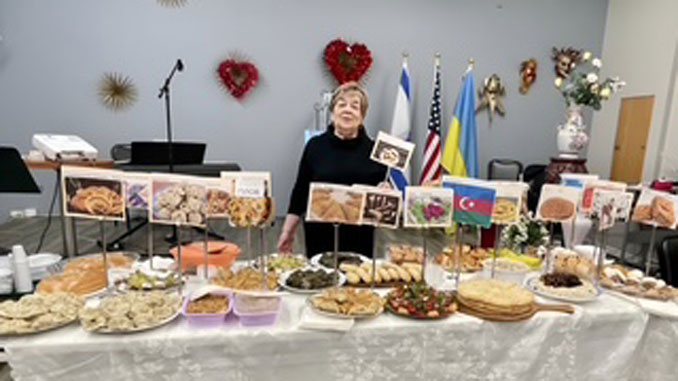 Директор культурно-просветительных программ Любовь Белл у стола с угощениями, приготовленными участниками центра Forever Young. Фото: Т. Цикис